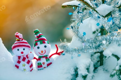 Preview: Two small funny toys baby snowman in knitted hats and scarves in deep snow outdoors