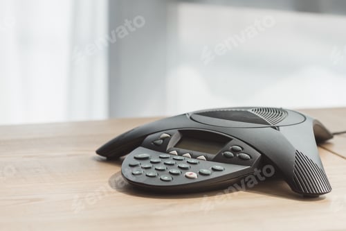Preview: close-up shot of conference phone on wooden table at office