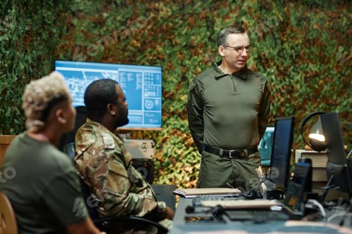 Preview: Confident mature male coach or officer looking at one of colleagues