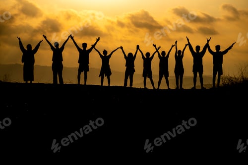 Preview: The silhouette of a group of people is celebrating success on the hilltop.