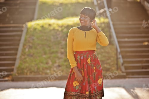 Preview: African american girl at yellow and red dress at golden autumn fall park.