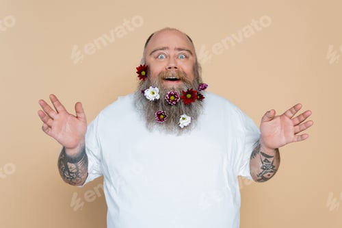 Preview: amazed overweight man with flowers in beard showing wow gesture isolated on beige