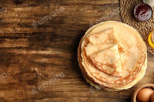 Preview: Flat lay composition with fresh thin pancakes on wooden table. Space for text