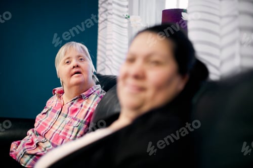 Preview: Mentally challenged woman sitting with friend on sofa at home
