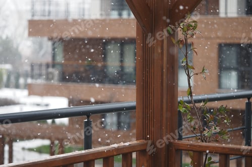 Preview: Snow falls gently on a balcony garden in a winter scene