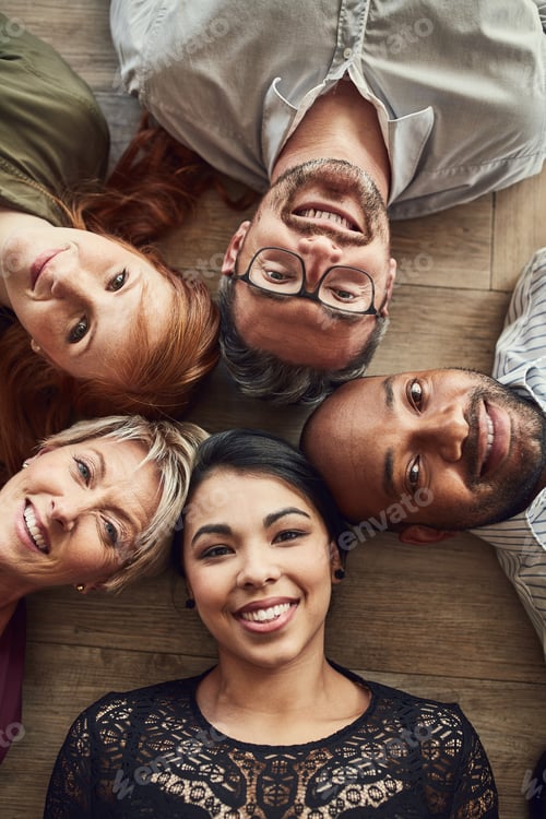 Preview: High angle portrait of a group of colleagues lying together in a circle on the floor at work