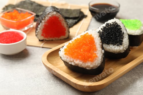 Preview: Tasty tobiko onigiri (Japanese rice balls) served on light grey table, closeup