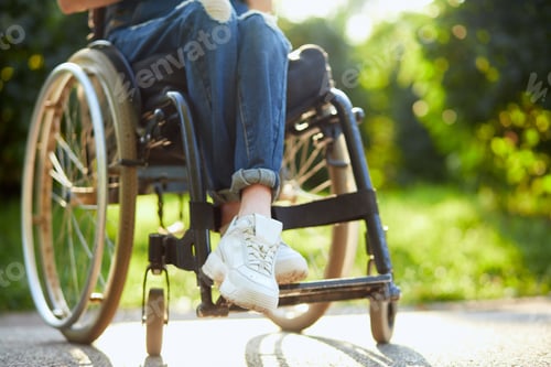 Preview: young disabled girl in overall sitting with crossed legs on the wheelchair