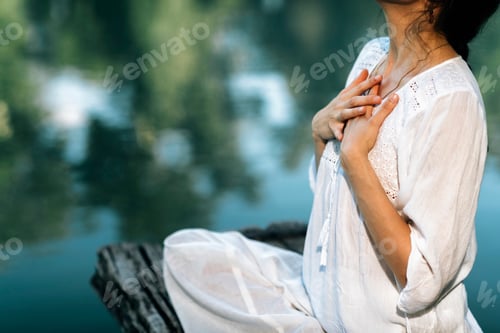 Preview: Yoga Retreat. Peaceful Young Woman Sitting in Lotus Position and Meditating by the Lake