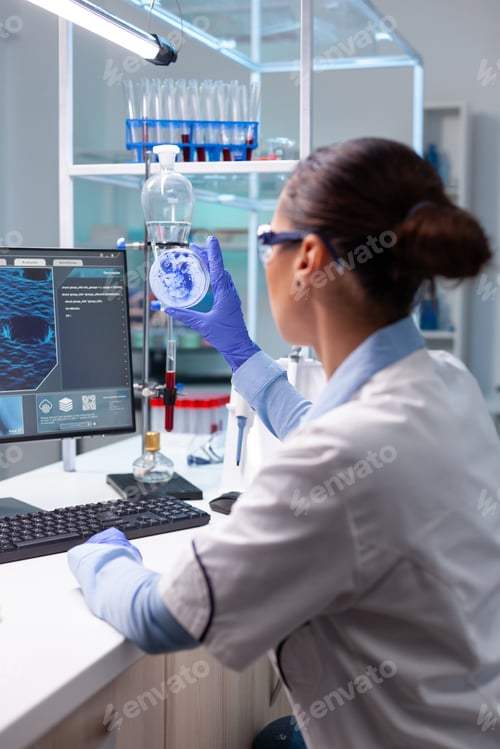 Preview: Biologist woman looking at bacteria virus using medical petri dish working at genetic infection