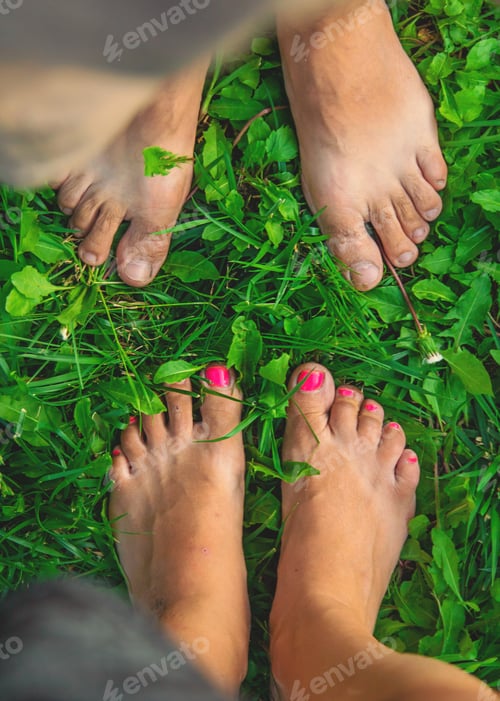 Preview: Legs of a woman and a man on the grass. Selective focus.