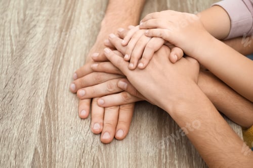 Preview: Happy family holding hands at wooden table, closeup view
