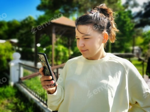 Preview: Teenage Girl Uses Her Phone Outside on Sunny Day