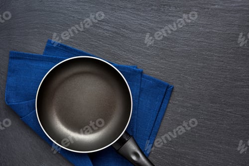 Preview: Empty frying pan over dark grey stone background. Top view