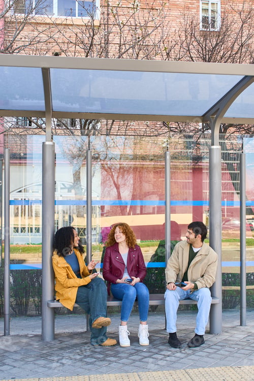 Preview: Students chatting and using their smartphones while waiting at the bus stop