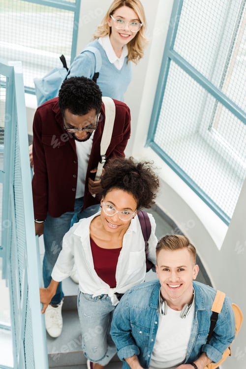 Preview: overhead view of four smiling multiethnic students with backpacks on stairs