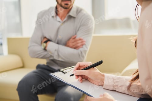 Preview: cropped view of patient and psychologist writing diagnosis in clipboard in office