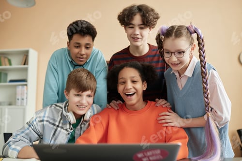 Preview: Cheerful school children using laptop computer in class