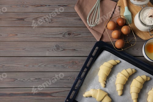 Preview: Raw croissants, ingredients and kitchenware on wooden table, flat lay. Space for text