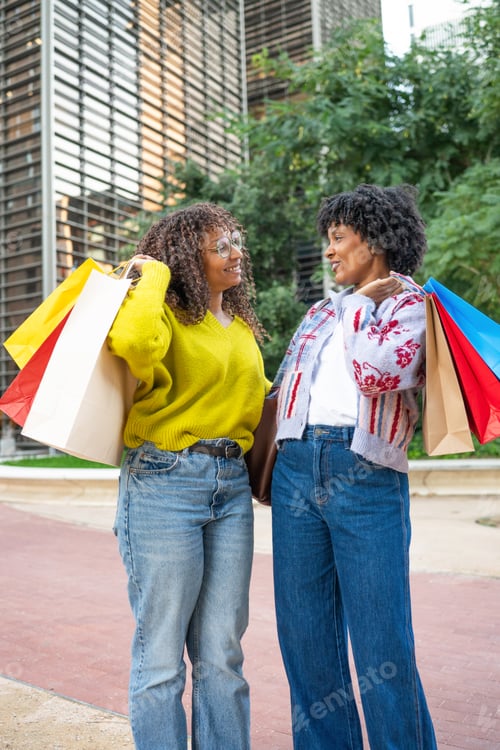 Preview: Smiling black women friends enjoying urban shopping day