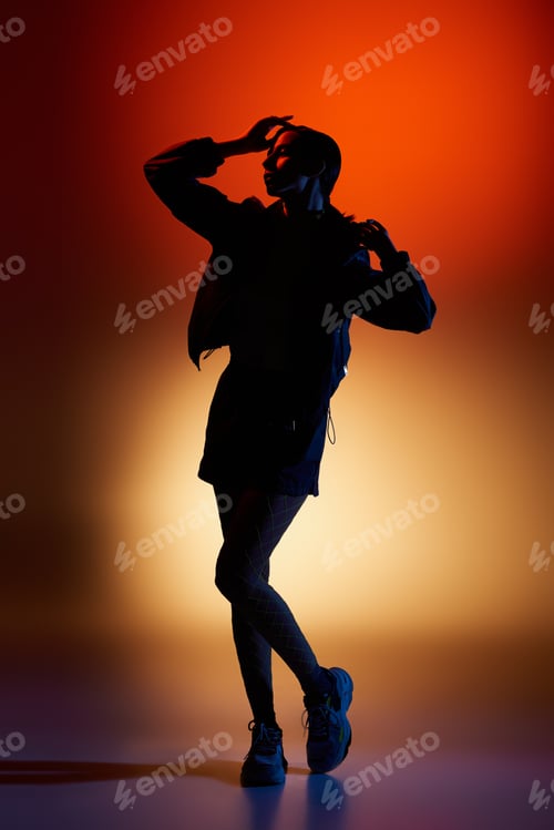Preview: Young woman poses elegantly in a vibrant studio with dramatic lighting