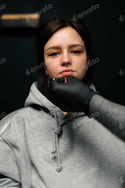 Preview: a girl at a session of nose piercing septum emotions close-up earring in nose