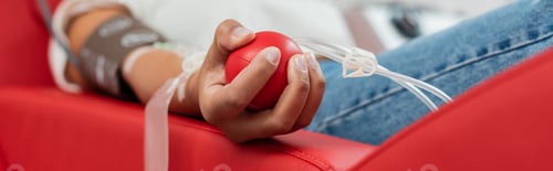 Preview: partial view of multiracial woman with transfusion set holding rubber ball while sitting