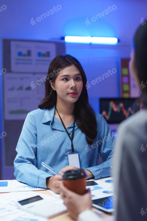 Preview: Businesswomen working late in office discussing over financial charts and graphs