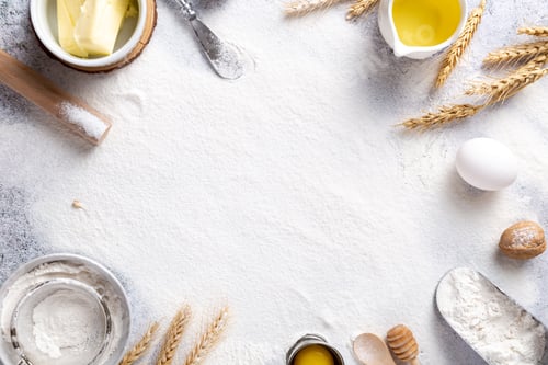 Preview: Top view shot of flour in the kitchen's table with spoons, buuter, eggs and plates