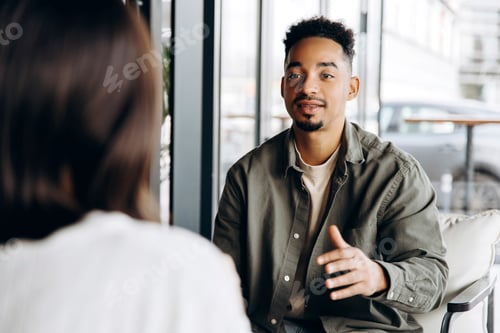 Preview: Young man explaining something to colleague during business meeting in cafe