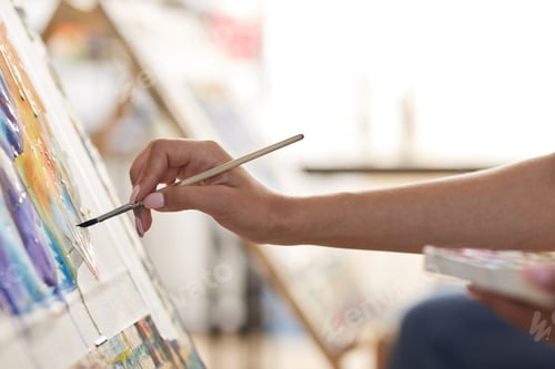 Preview: Girls hand holds a paint brush. Process of painting picture at the easels in the art studio