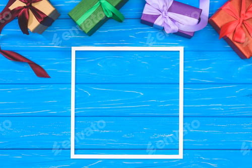 Preview: top view of gift boxes and blank frame on blue table