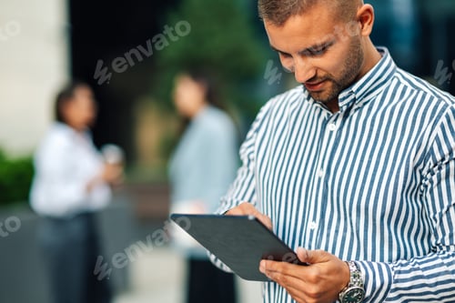 Preview: Businessman using digital tablet outside office building