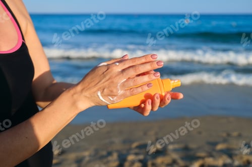 Preview: Close up of woman applying suntan lotion, sand beach blue sea background