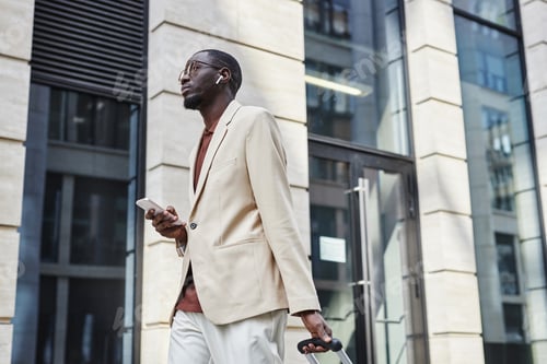 Preview: Busy young male ceo in quit luxury attire listening to music in earphones