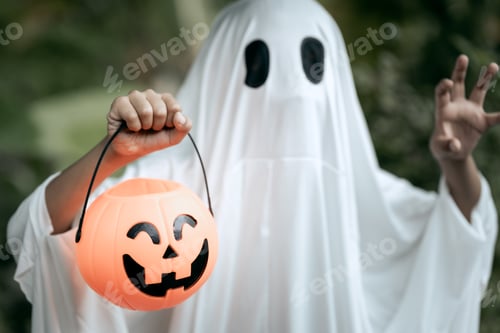 Preview: A young boy dressed as a ghost for Halloween wears a white sheet with black eye holes
