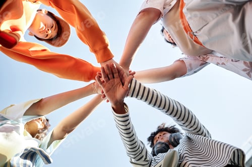 Preview: Four Teenagers Joining Hands Standing in Circle against Sky