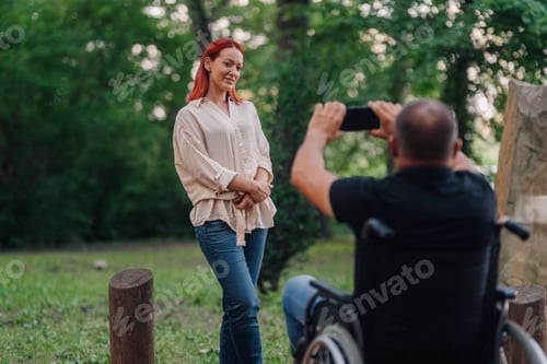 Preview: Photographer in wheelchair taking photos of woman in park