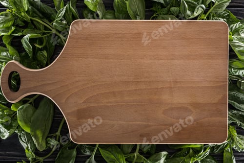 Preview: top view of wooden cutting board on leaves of basil