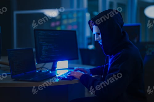 Preview: An anonymous hacker wearing a mask and hoodie in a dark room
