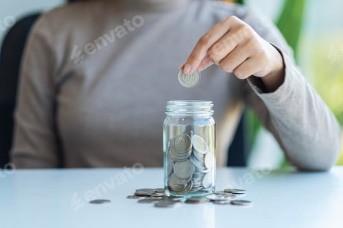 Preview: Woman Putting Coins Into Glass Jar on Table