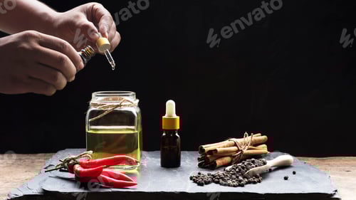 Visualização: Pipeta segurando a mão, frasco conta-gotas com várias ervas e óleo essencial de ervas em fundo escuro