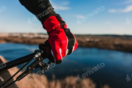 Preview: close up view of a Cyclist equipment glove and handlebar. Man Riding the Bike Down Rocky Hill