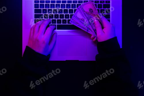 Preview: Money in male hands on the background of a laptop keyboard in neon lighting.