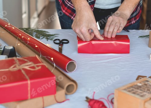Preview: Woman is wrapping Christmas present in red wrapping paper