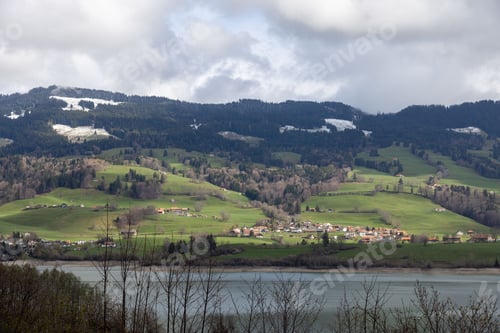 Preview: mountainous landscape in Switzerland covered with snow and partly in the clouds with Greyerzersee