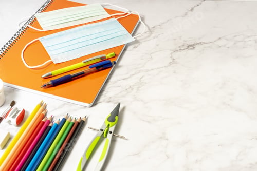 Preview: Compass, sanitary mask, colored pencils, notebooks, sharpener, brush, rubber on a marble table
