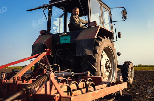 Preview: Portrait of satisfied farmer sitting in a tractor preparing to cultivate the land with a tractor.