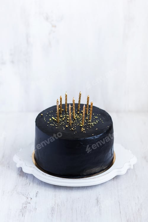 Visualização: Bolo de aniversário preto com velas douradas sobre fundo branco