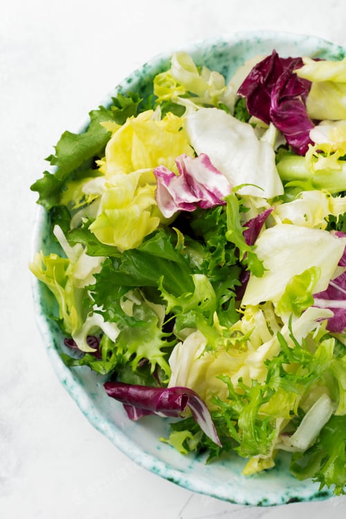 Preview: Fresh leaves of different salad in ceramic plate on white stone background. Selective focus. Top vie